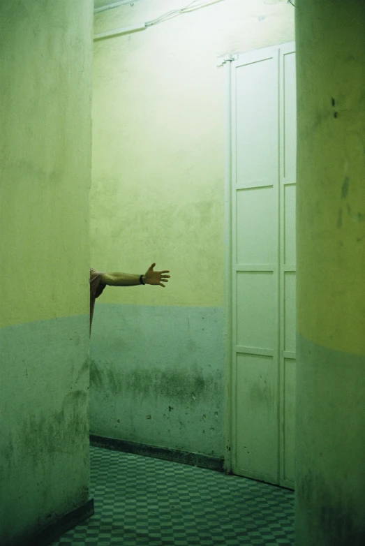 the arm of someone reaching out from behind a doorway