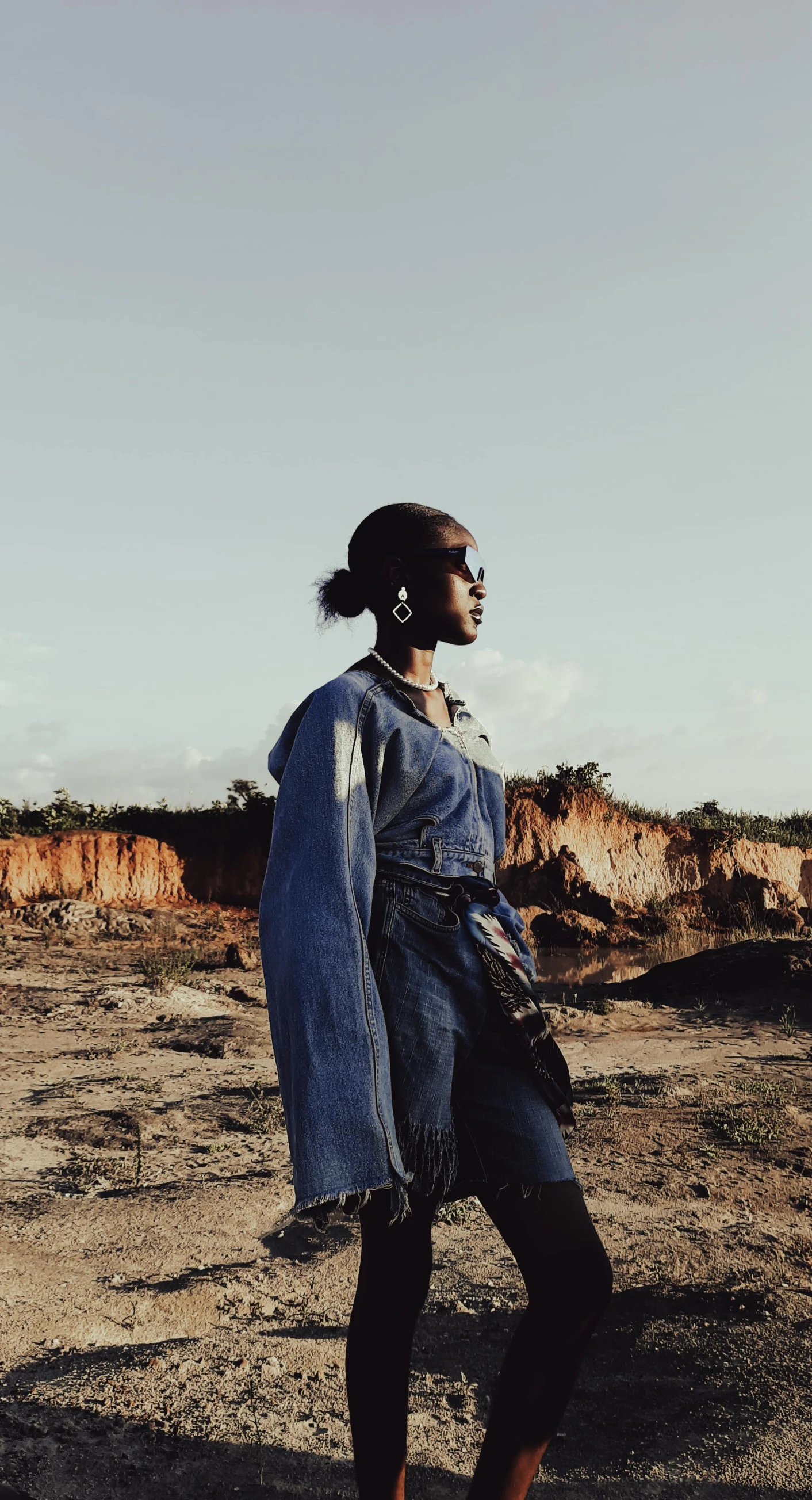 a woman standing in a desert with a denim jacket on