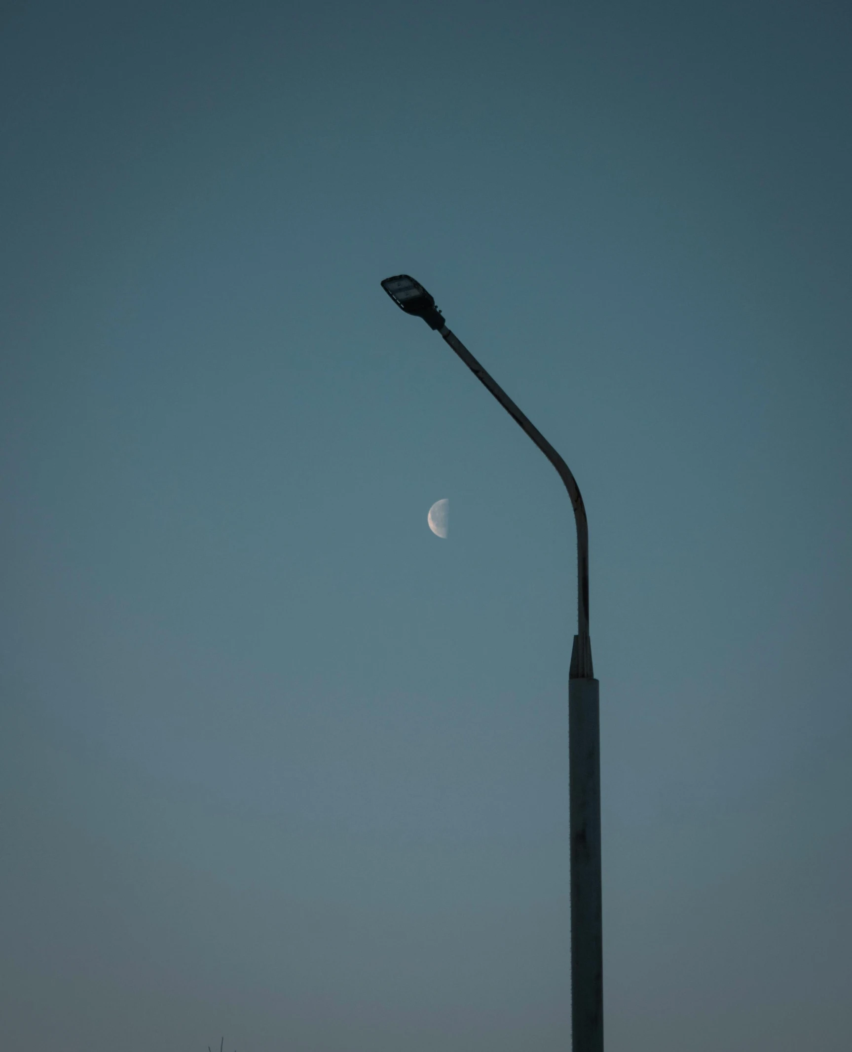 the moon is in the distant sky on this street lamp