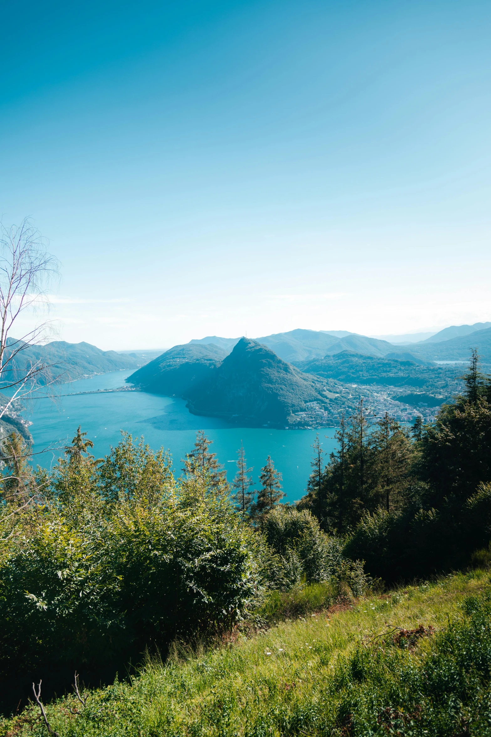 view of a lake surrounded by mountains from a hilltop