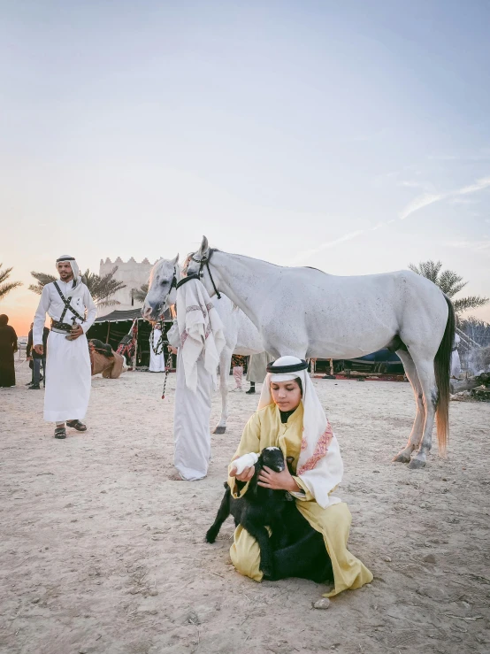 a woman is kneeling in the sand next to her horse