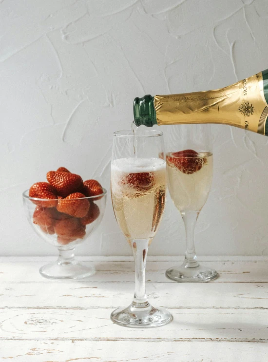 two glasses filled with champagne and some strawberries