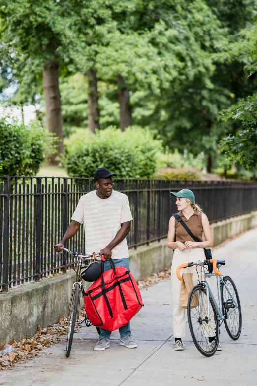 a couple of people riding bikes down a street next to a fence