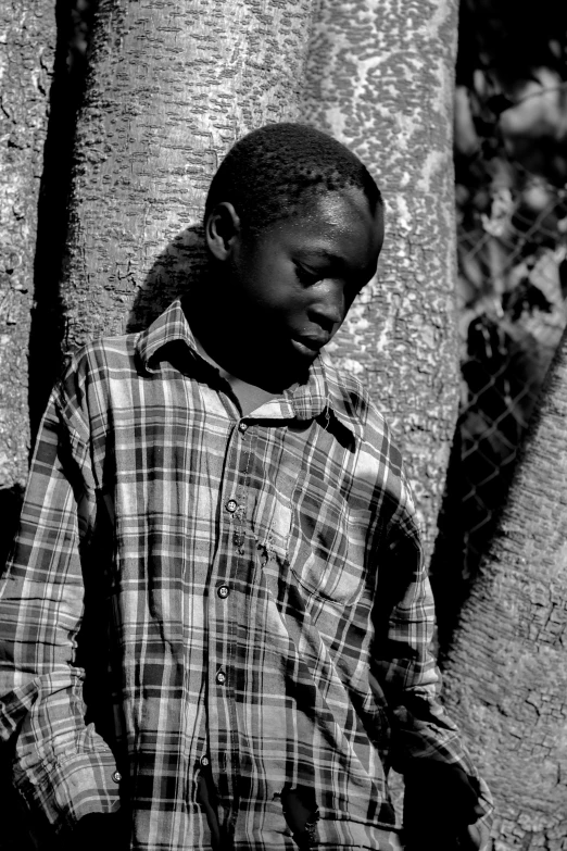 an african man stands in front of a tree