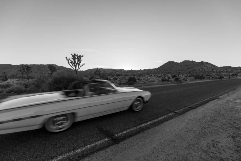 a classic american convertible car driving down a country road