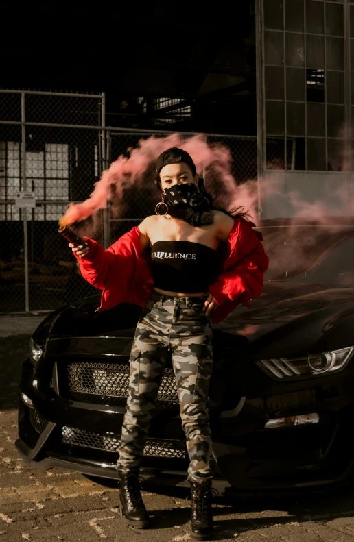 a woman wearing tight, camo pants and heels standing in front of a car smoking