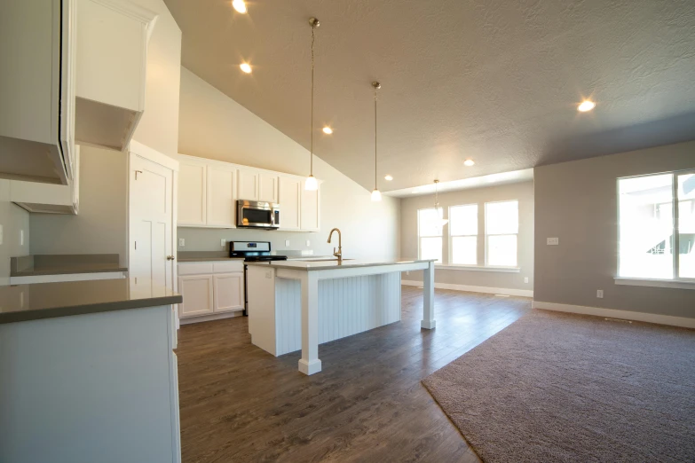 a large open kitchen and living room with white cabinets and counter tops