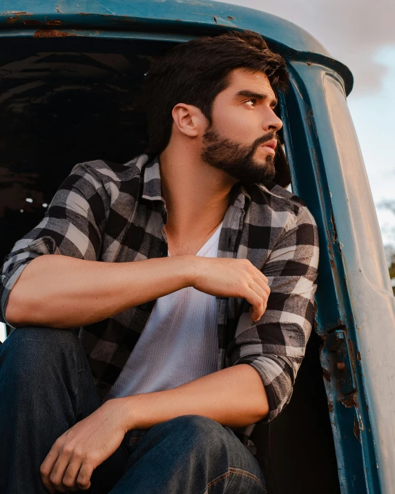 man with plaid shirt in the back of a pick up truck