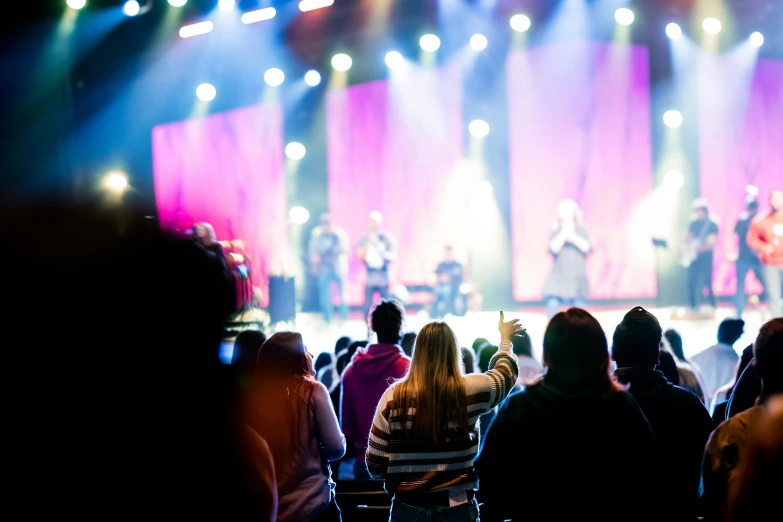 people are seated on a stage watching a man perform