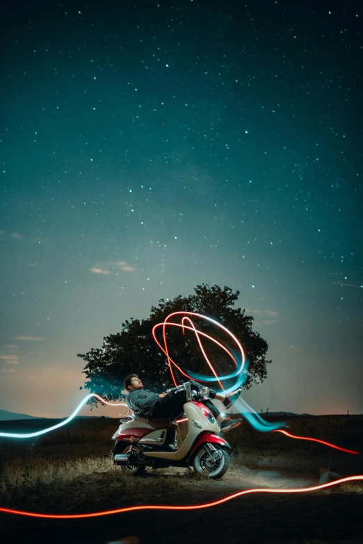 a person rides their motor scooter as a long exposure of a night sky