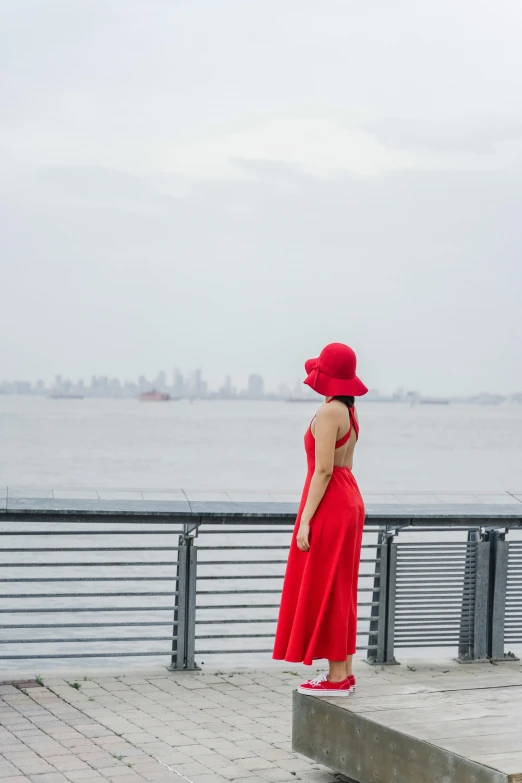 the young woman is standing on the side walk looking out to sea