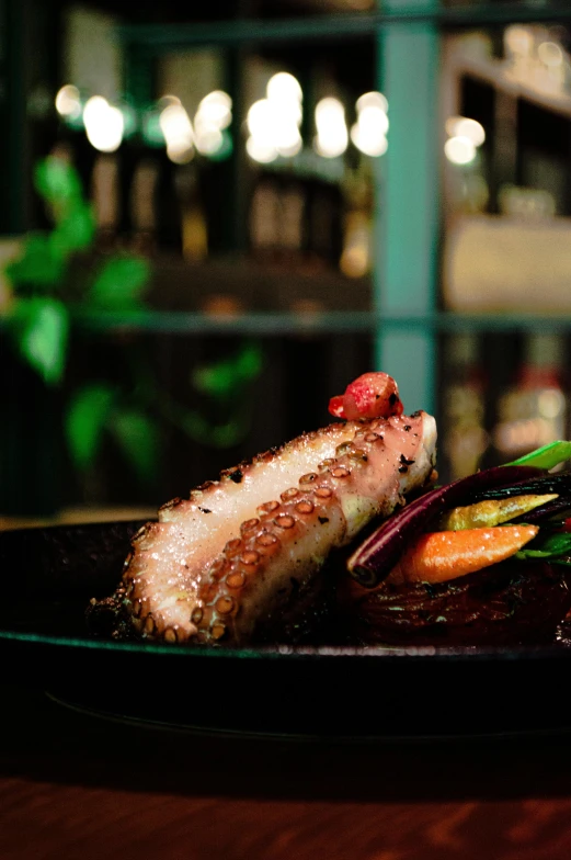 a black plate with a meat and vegetables on it