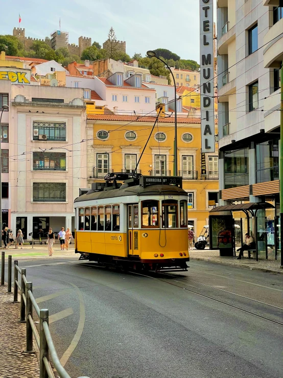 a yellow trolley passes in front of tall buildings