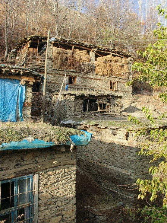 a run down house in the woods with clothes hanging from it