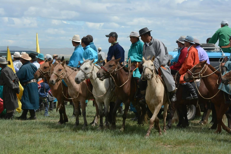 people on horses in a line with other people standing around