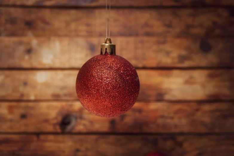 an ornament hanging from strings against a wooden wall