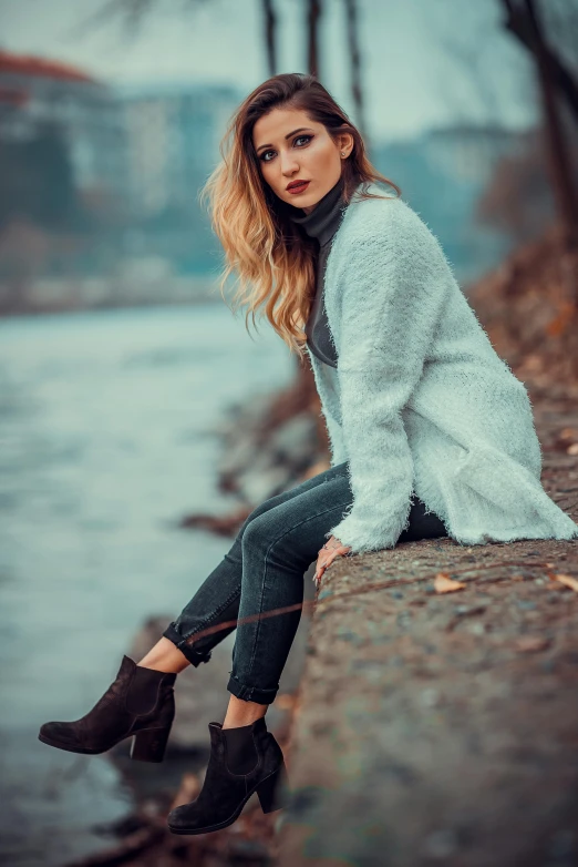 a girl with long blonde hair posing in boots by the water