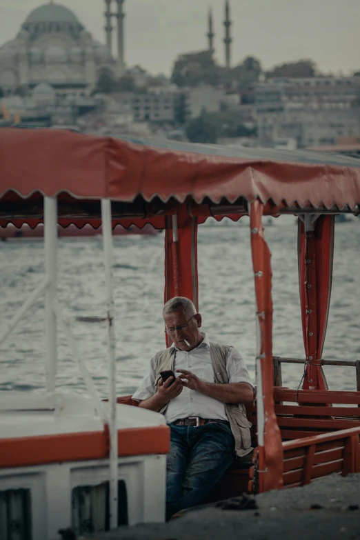 an old man on a boat, using a cellphone