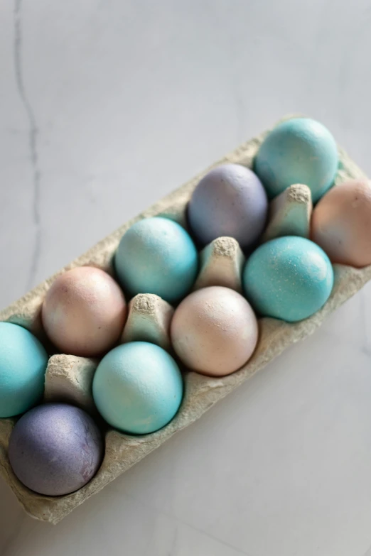 a cardboard tray filled with assorted colored eggs