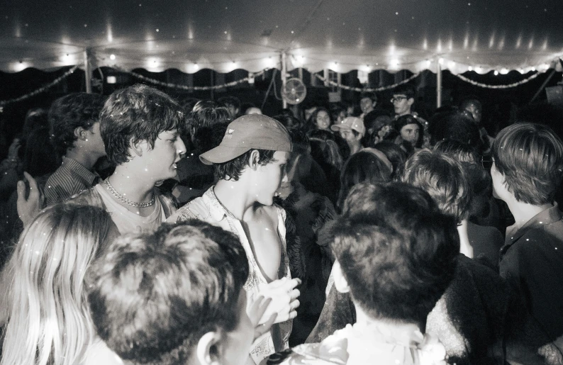 crowd of people standing in front of tent with lights