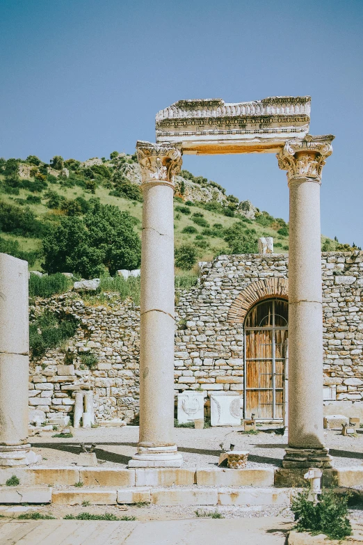 a building with many white pillars sitting next to a hill