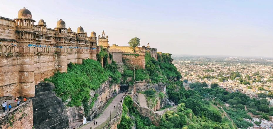 a city sitting above a hillside covered in lush green trees