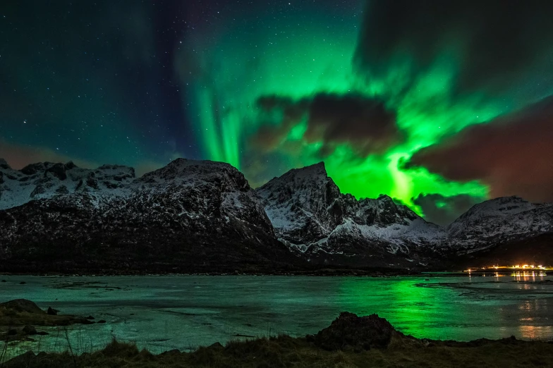 a green and red aurora above some mountains