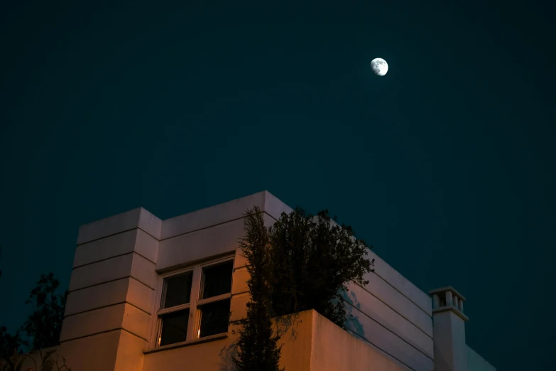 the moon in a dark sky is shining brightly over a building