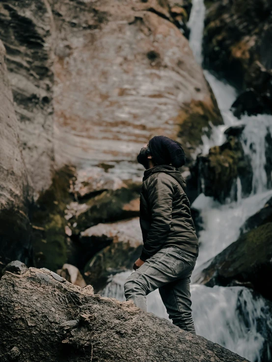 there is a person standing on a rock by a waterfall