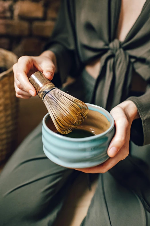 the woman is holding her hand in a cup with some tea