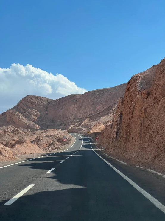 a road with mountains and some clouds near by