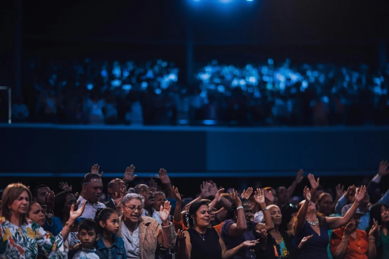 large group of people are clapping for an audience