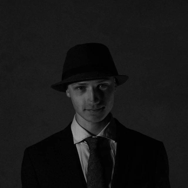 a man in a hat and suit wearing a tie