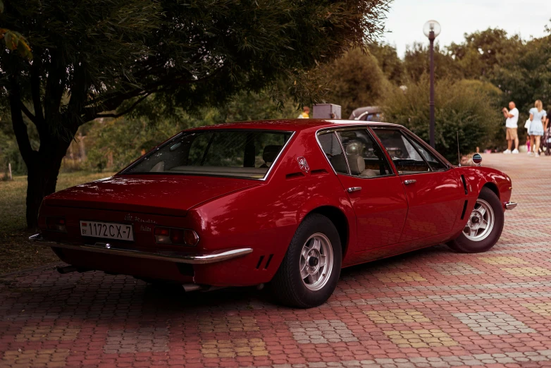 a red sports car sits on a brick patio