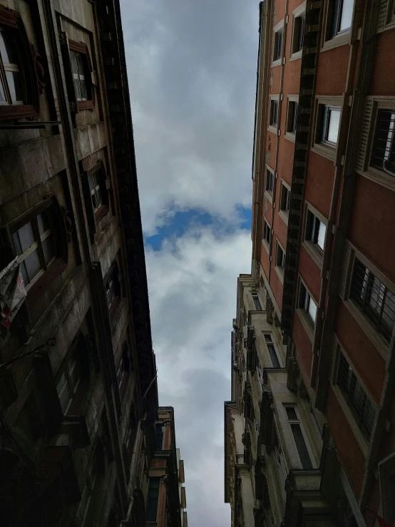 view of tall buildings from between them looking up at the sky