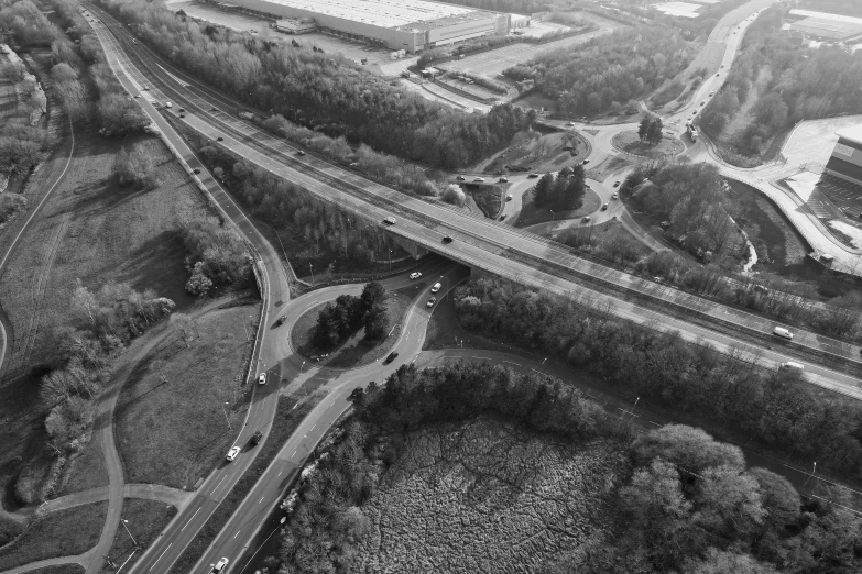 a black and white pograph of a road, traffic and trees