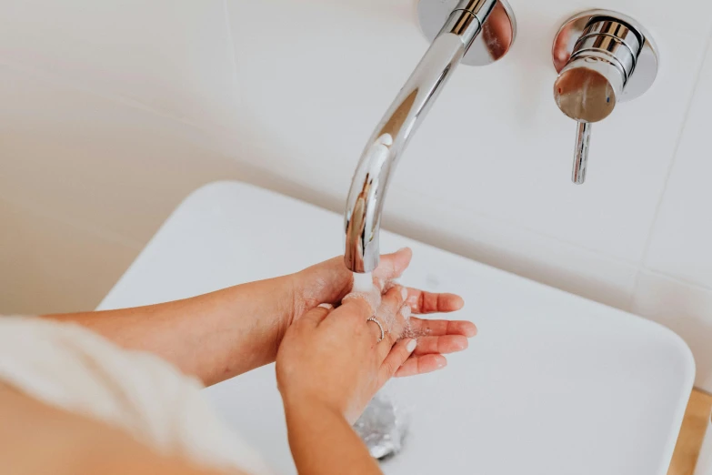 woman washing hands under running water from a faucet