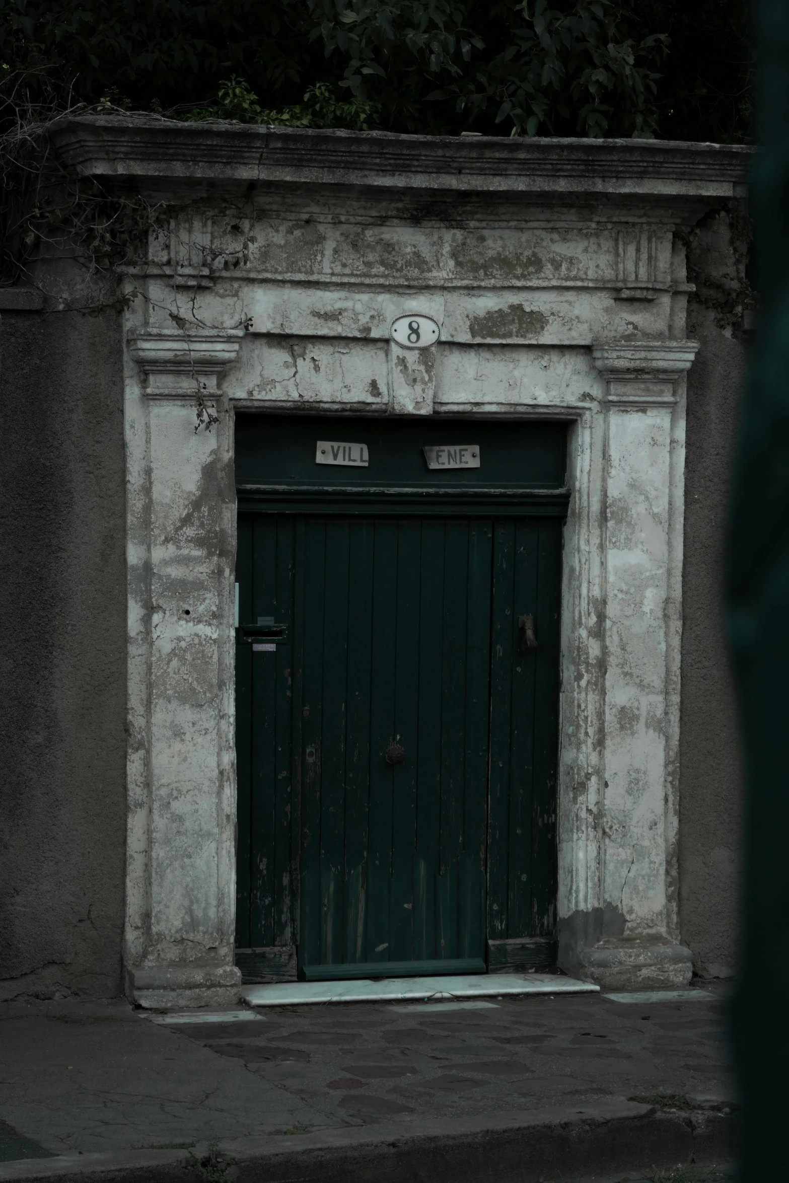 an old and grungy building with a large green door