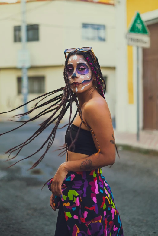 a woman with dreadlocks and makeup is wearing a colorful outfit