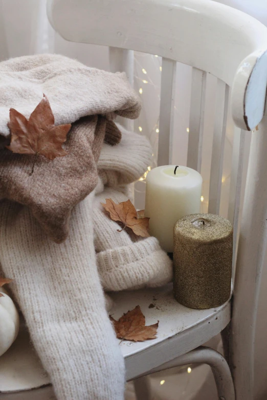 a wooden chair with fall leaves and candles on top