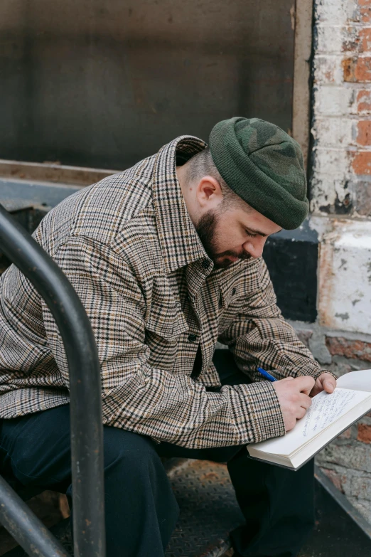 a man sitting on a metal hand rail writing