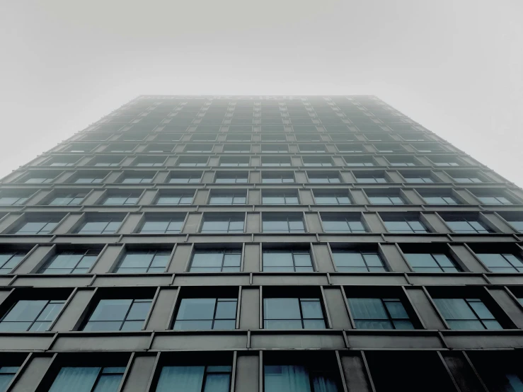 a tall building is covered with windows while the sky peeks