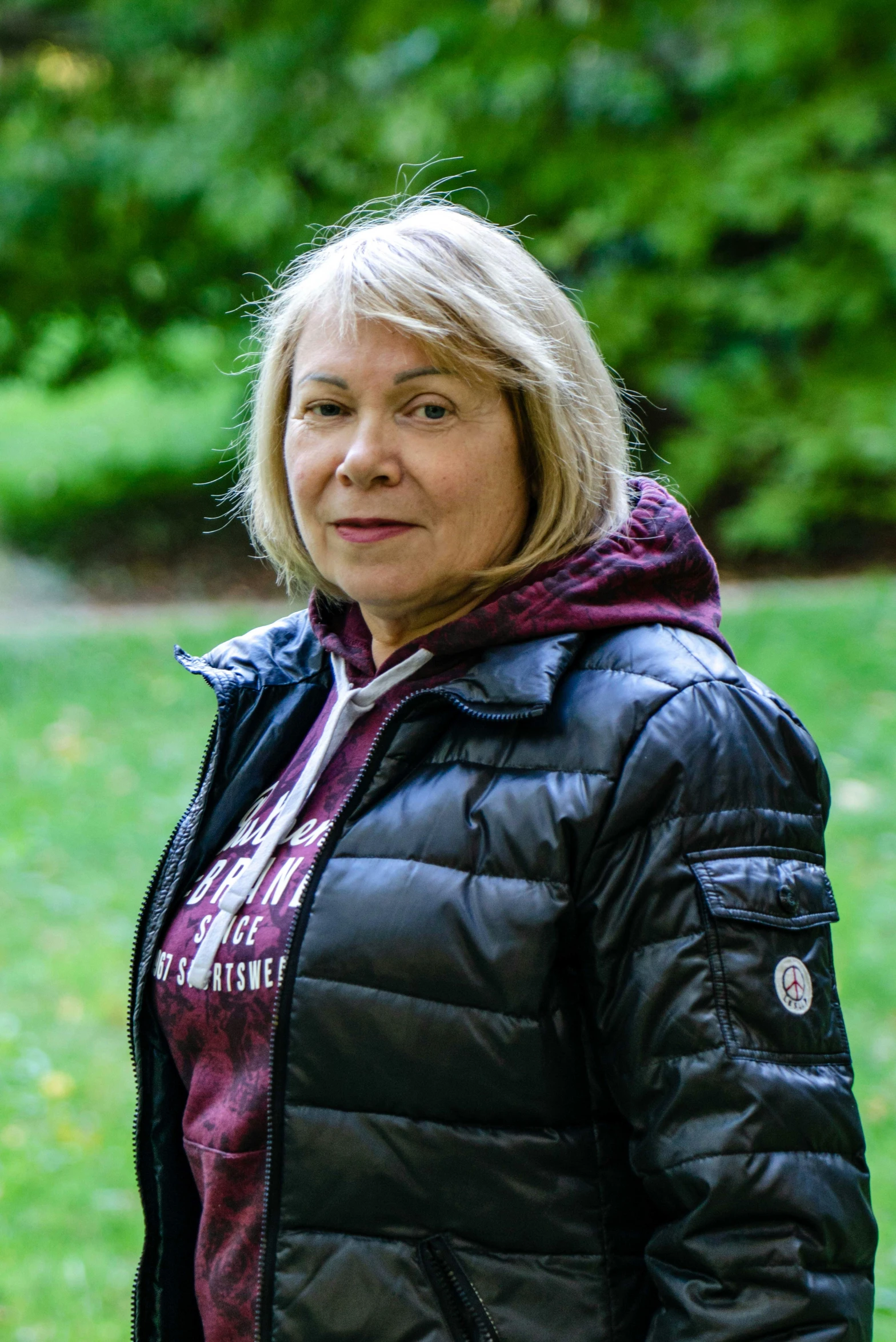 a woman in black coat standing on grass