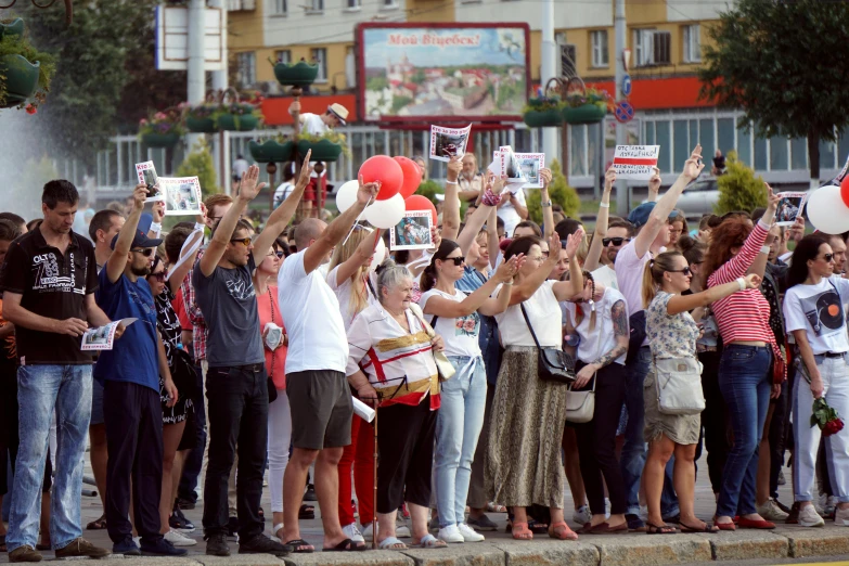 the people are standing outside holding up their hands