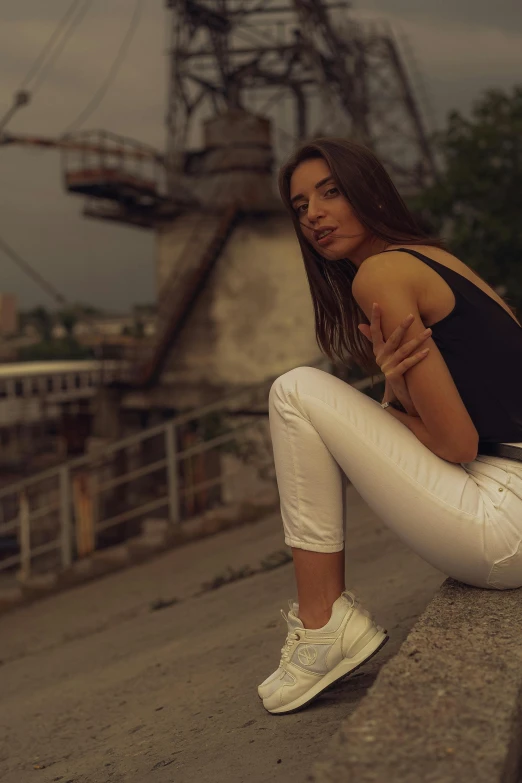 a woman sitting on the edge of a bridge and wearing athletic clothes