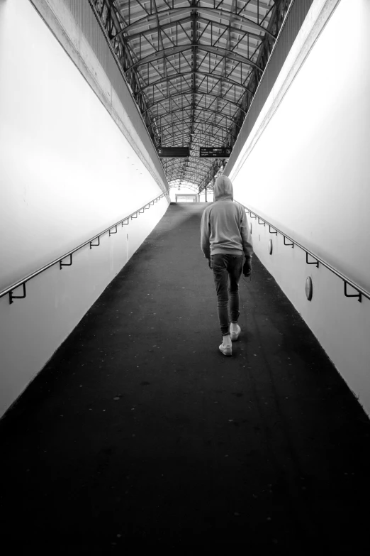 black and white image of a man walking down the walkway