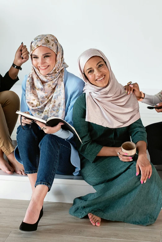 three women sitting on a bench one wearing a headscarf and the other a scarf