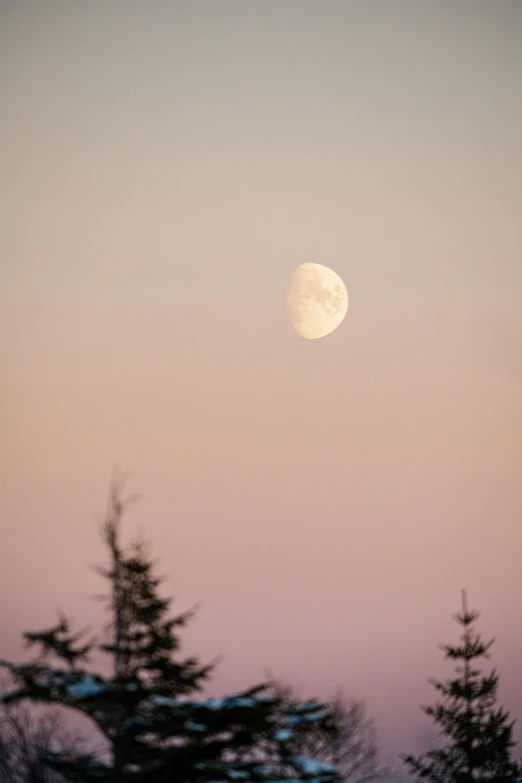 the moon is setting on the top of a mountain