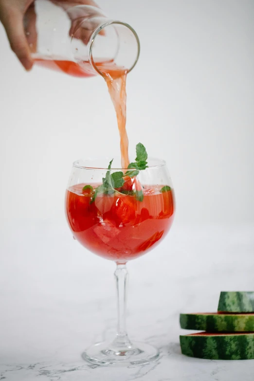 someone filling a drink into a glass filled with liquid