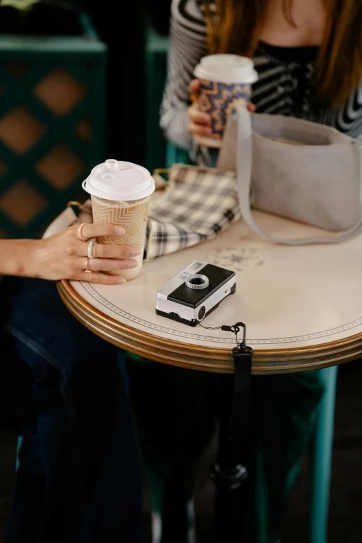 two people sitting at a table with cups of coffee